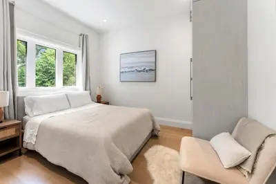 a white bedroom with a bed and a chair at Luxury Home - 5 min from airport, 15 to downtown in Toronto