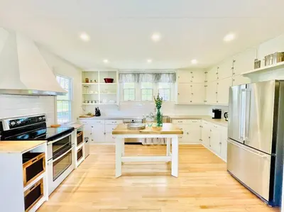 a white kitchen with a table and a refrigerator at Waterfront Niagara-On-The-Lake Farmhouse on a Vineyard in Niagara on the Lake