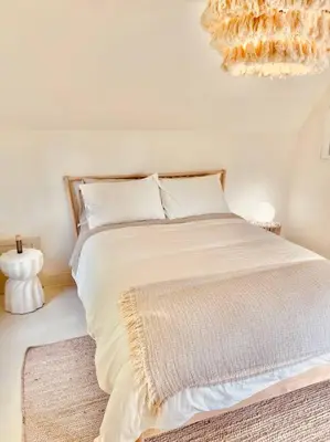 a bedroom with a bed with white sheets and a chandelier at Waterfront Niagara-On-The-Lake Farmhouse on a Vineyard in Niagara on the Lake