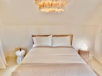 a bedroom with a large bed with a chandelier at Waterfront Niagara-On-The-Lake Farmhouse on a Vineyard in Niagara on the Lake