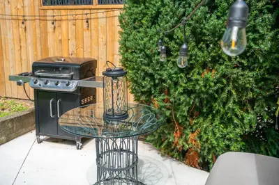 a grill and a glass table next to a bush at Queenston Cottage in Queenston
