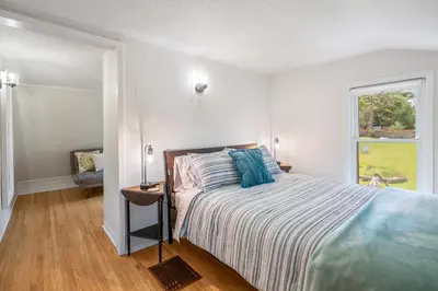 a white bedroom with a bed and a window at Queenston Cottage in Queenston
