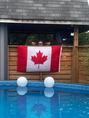 a man holding a canadian flag over a swimming pool at Sunset Suites in Niagara Wine Country in Niagara on the Lake