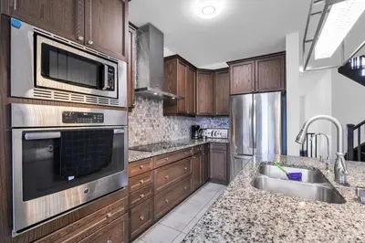 a kitchen with stainless steel appliances and wooden cabinets at Entire 6BR 2 king 8 beds in total pets 3 GB WiFi in Kitchener