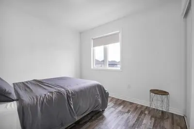 a white bedroom with a bed and a window at Entire 6BR 2 king 8 beds in total pets 3 GB WiFi in Kitchener