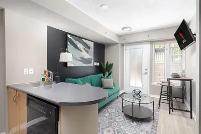 a kitchen and living room with a green couch at Lakeside Haven - Cozy Townhome in Liberty Village in Toronto