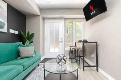 a living room with a green couch and a table at Lakeside Haven - Cozy Townhome in Liberty Village in Toronto