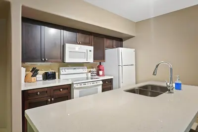 a kitchen with white appliances and wooden cabinets at King Bed, Balcony, Pool, Hot Tub, Sauna in Edgar