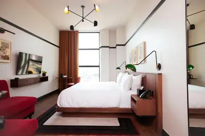 a bedroom with a white bed and a red chair at The Postmark Hotel in Newmarket