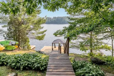 a wooden pathway leading to a dock on a lake at Muskoka Lakeshore Cottage Bliss in Gravenhurst