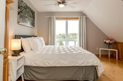 a bedroom with a large bed with a window at Muskoka Lakeshore Cottage Bliss in Gravenhurst