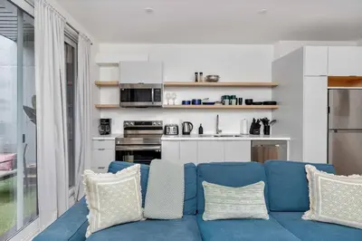 a living room with a blue couch and a kitchen at Hidden Gem - 3 BR Steps to Little Italy and UofT in Toronto