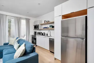 a living room with a blue couch and a kitchen at Hidden Gem - 3 BR Steps to Little Italy and UofT in Toronto