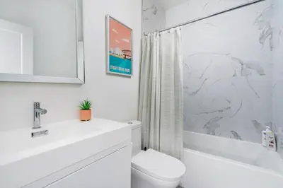 a white bathroom with a toilet and a sink at Hidden Gem - 3 BR Steps to Little Italy and UofT in Toronto
