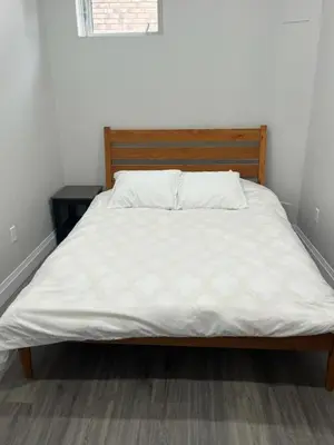 a bed with white sheets and a wooden headboard at 2BR 1 king 1 Queen with parking 3 GBPS internet in Kitchener