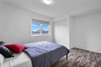 a white bedroom with a bed and a window at 4BR 2 king 3 Queen 6 beds in total 3 GBPS Wi-Fi in Kitchener