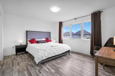 a bedroom with a bed and a desk and a window at 4BR 2 king 3 Queen 6 beds in total 3 GBPS Wi-Fi in Kitchener