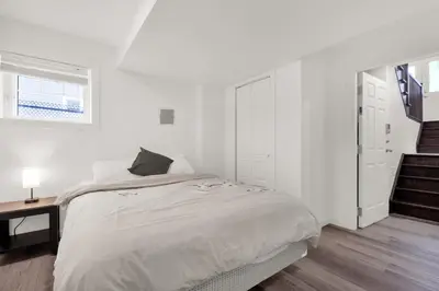 a white bedroom with a bed and a window at Modern 2BR Duplex 3.0 GBPS internet with Parking in Kitchener