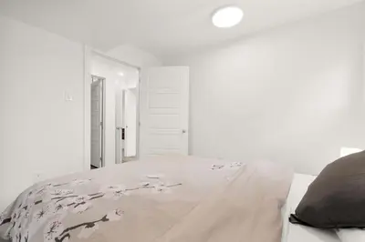 a white bedroom with a bed with flowers on it at Modern 2BR Duplex 3.0 GBPS internet with Parking in Kitchener