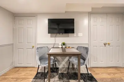 a dining room with a table and chairs and a tv at Modern, basement apartment, close to airport in Toronto
