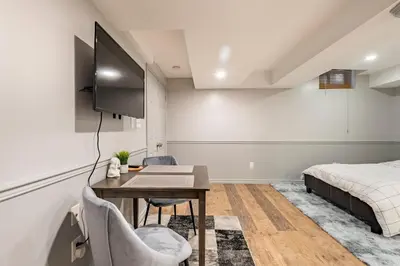 a bedroom with a desk and a bed and a television at Modern, basement apartment, close to airport in Toronto
