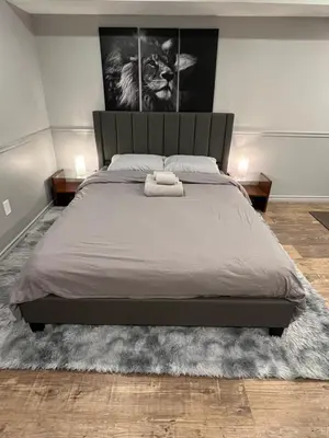 a bedroom with a large bed with a gray bedspread at Modern, basement apartment, close to airport in Toronto