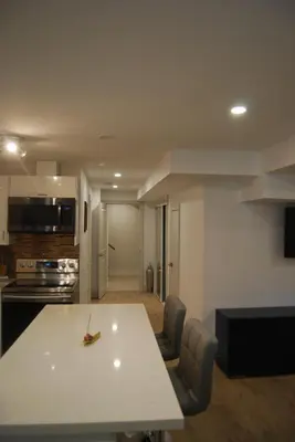 a kitchen and dining room with a white table and chairs at Modern 2-BR Basement Apartment in Richmond Hill