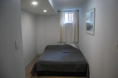a bedroom with a bed in a white room at Modern 2-BR Basement Apartment in Richmond Hill