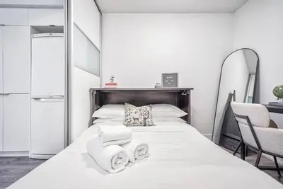 a bedroom with a white bed with towels on it at Designer 2BR Downtown Condo, Rogers Center in Toronto