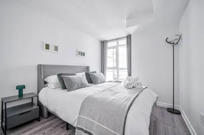 a white bedroom with a large bed with a teddy bear on it at Designer 2BR Downtown Condo, Rogers Center in Toronto
