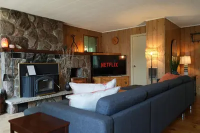 a living room with a blue couch and a stone fireplace at Mary Lake Sunset Lodge in Port Sydney