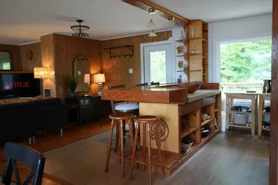a kitchen and living room with a counter and stools at Mary Lake Sunset Lodge in Port Sydney