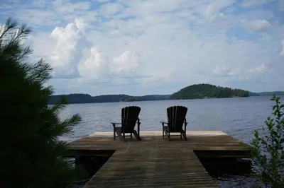 two chairs sitting on a dock on a lake at Mary Lake Sunset Lodge in Port Sydney