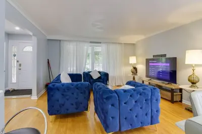 a living room with two blue chairs and a flat screen tv at Beautiful house near Eglinton GO in Toronto