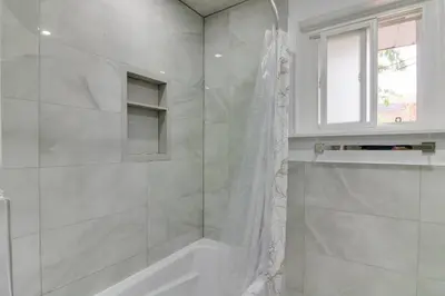 a white bathroom with a shower and a window at Beautiful house near Eglinton GO in Toronto