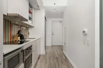 a kitchen with white walls and a wooden floor at 1BD next to Queen St - most ideal location in Toronto