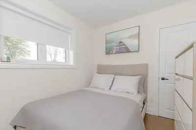a white bedroom with a bed and a window at South Oakville Bliss Haven Monthly Stays only in Oakville