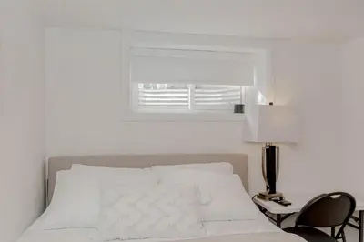 a white bedroom with a bed and a window at South Oakville Bliss Haven Monthly Stays only in Oakville