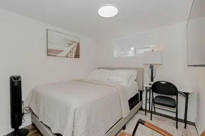 a white bedroom with a bed and a chair at South Oakville Bliss Haven Monthly Stays only in Oakville
