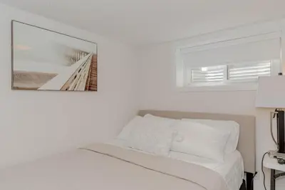 a white bedroom with a bed with a picture on the wall at South Oakville Bliss Haven Monthly Stays only in Oakville