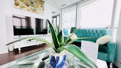 a living room with a blue couch and a glass table with a plant at Superior Lakeview Luxury 3-Bedroom Suite on High Floor in Toronto