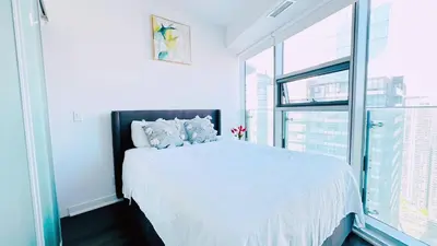 a bedroom with a white bed and a large window at Superior Lakeview Luxury 3-Bedroom Suite on High Floor in Toronto