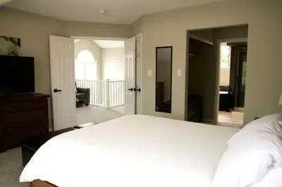 a bedroom with a large white bed and a television at Cozy, 4 Bedroom Chalet, 10 min walk to Village in Blue Mountains