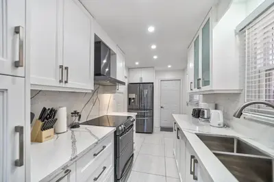 a kitchen with white cabinets and a stove top oven at 4BR Scarborough Gem, Freshly Renovated, 7 Car Parking in Toronto
