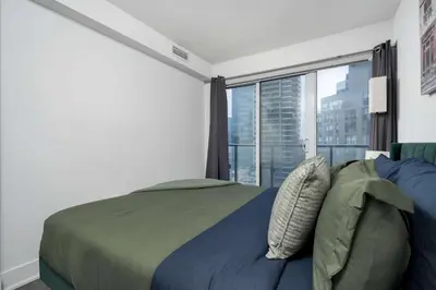 a bedroom with a bed and a large window at Pleasant 1BR Sofa Bed Close to UofT in Toronto