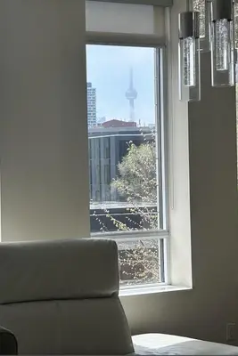 a window with a couch and a view of a city at 1560 sqft Elegant Condo at Downtown Hi-End Shopping & Dining Area - CN Tower View, Bidet, LockBox in Toronto