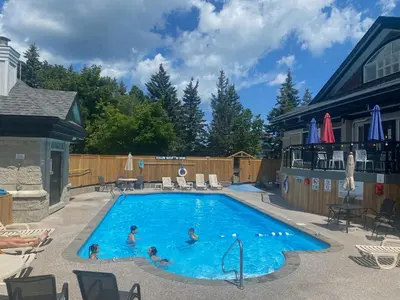 a large swimming pool with people in the water at 1 Bed, 1 Bath Lovely Open Concept Resort Condo in Blue Mountains