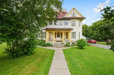 a white house with yellow trim and a driveway at Marmora and Lake Inn and Victorian Diner - Grand Victorian Suites- Level 2 in Marmora
