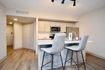 a kitchen with two white bar stools at a counter at Lux Jacuzzi Suite - Top Level in Shanty Bay