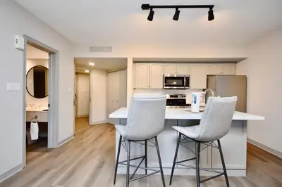 a kitchen with two white bar stools and a counter at Lux Jacuzzi Suite - Top Level in Shanty Bay